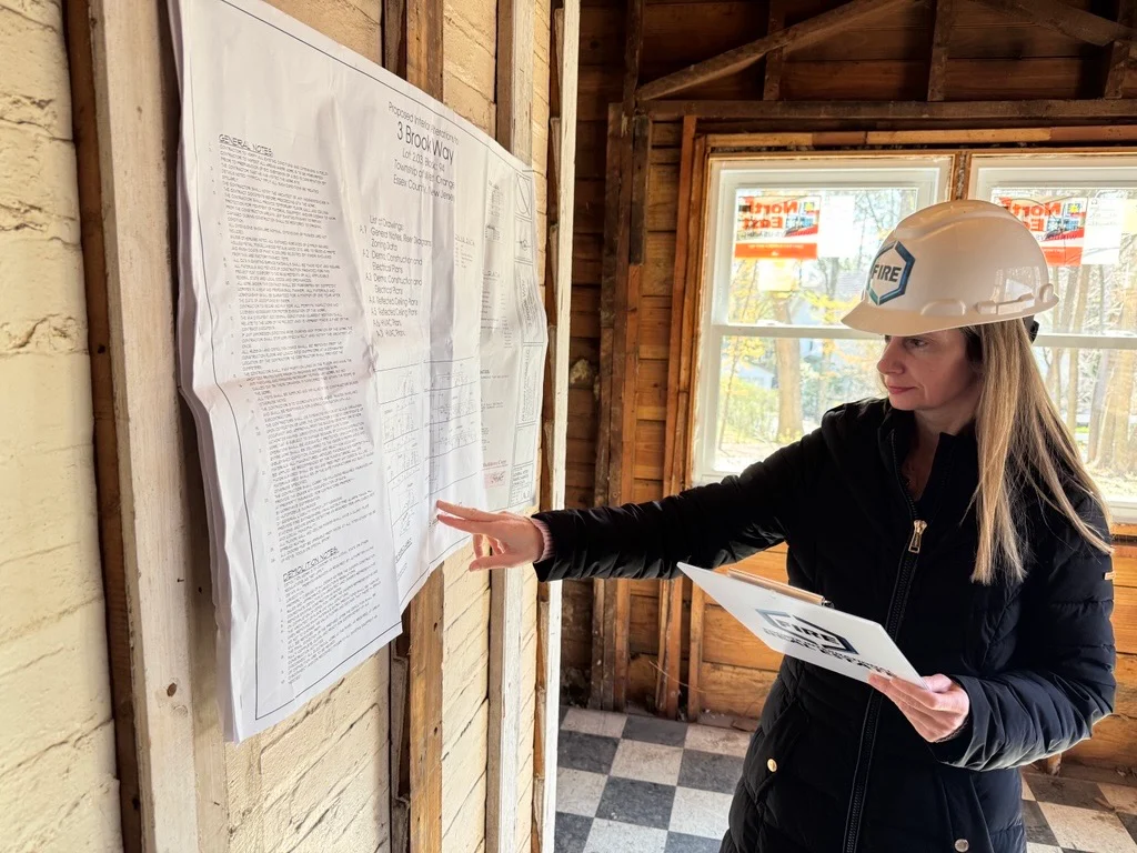 Mary Fourte reviewing drawings in the unfinished interior of 3 Brook Way